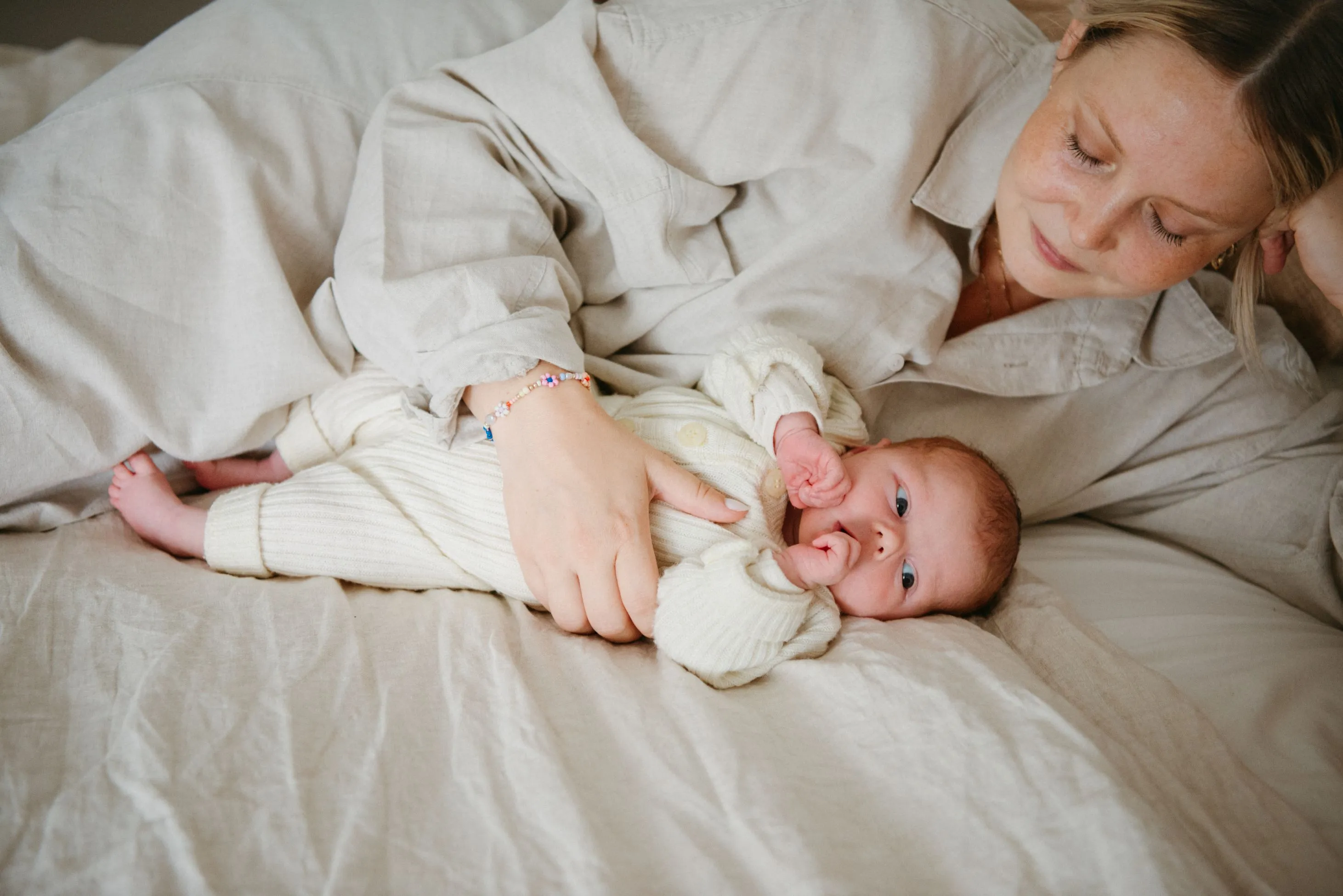 Mother holding newborn baby in bed
